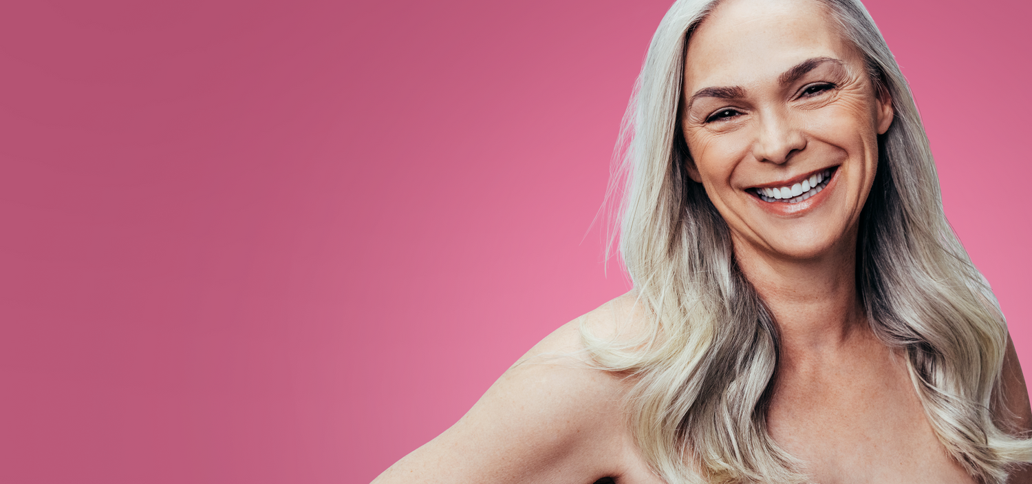 Woman with blonde hair smiling against a pink background