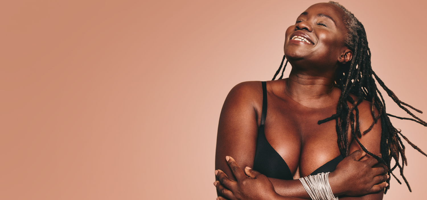 Woman wearing a black bralette against a beige background