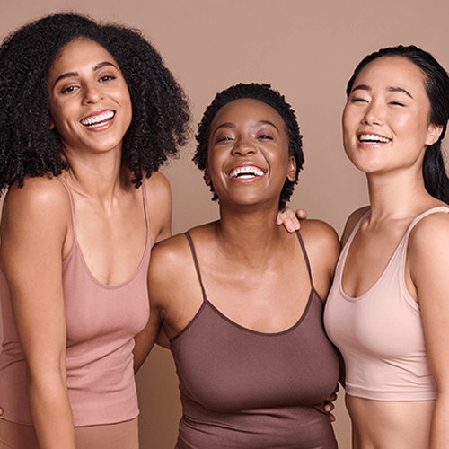 Three diverse women wearing tank tops against a beige background